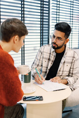Man showing something in notebook and looking at female colleague