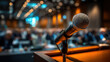 © Keopaserth - Microphone on podium in conference hall with blurred audience and warm lighting creating engaging atmosphere for public speaking or presentation event