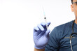 © ArvStd - Confident asian male nurse, doctor in medical rubber gloves, holding syringe with vaccine, standing white background