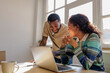 © BONNINSTUDIO/Stocksy - Coworkers smiling and collaborating on laptop in modern office
