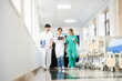 © Santi Nuñez/Stocksy - Medical team walking through hospital corridor using tablet