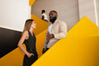 © VICTOR TORRES/Stocksy - Colleagues Discuss Work on Yellow Staircase in Modern Office