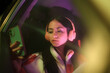 © Lucas Ottone/Stocksy - Night colorful portrait of woman with phone and headphones in a car