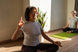 © Alvaro Lavin/Stocksy - Mature women practicing gyan mudra yoga position during group lesson