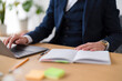 © Studio Marmellata - A businessman in a suit works at his desk. He is typing on a laptop and has a notebook open next to him, ready to take notes.