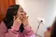 © Lupe Rodriguez/Stocksy - young woman with acne looking in her bathroom mirror
