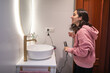 © Lupe Rodriguez/Stocksy - young woman fixing her hair in the bathroom