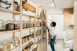 © David Prado/Stocksy - Employee Organizing Jars on Shelves in Bulk Food Store