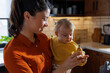 © Jovo Jovanovic/Stocksy - Woman holding cute daughter eating fruit