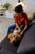 © Jovo Jovanovic/Stocksy - woman changing diaper of daughter on sofa at home