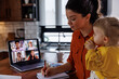 © Jovo Jovanovic/Stocksy - Mother with daughter attending online meeting at home