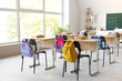 © Pixel-Shot - Interior of light classroom with desks, backpacks on chairs and blackboard