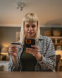 © Miljan Živković - Young woman using smart phone shopping online holding credit card home