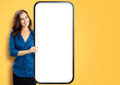 © vgstudio - Portrait image - happy smile cute businesswoman business woman show point big mockup cell phone, modern smartphone mobile cellphone with blank white screen, isolated yellow background. Online offer ad