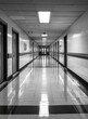 © Rika - Empty, reflective corridor in a monochrome hospital.
