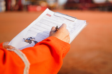 Wall Mural - a maintenance engineer is checking on checklist to verify the condition of forklift or heavy machine