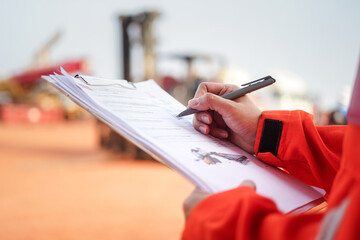 Wall Mural - a maintenance engineer is checking on checklist to verify the condition of forklift or heavy machine