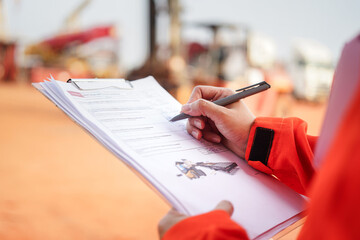 Wall Mural - a maintenance engineer is checking on checklist to verify the condition of forklift or heavy machine