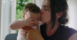 © Marco - Mother kisses her baby on the cheek while holding them in her arms, creating a tender and loving moment, highlighting the strong bond and affection in a cozy home environment-SD 480p