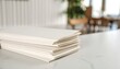 © Chatchawan - Stack of Blank Paper Sheets on a Table in a Cafe Setting Perfect for Mockups and Design Presentations