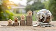 © picbox - Closeup of a small wooden model house on the top of a stack of golden coins, on a wooden shelf or table with copy space.