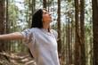 © boryanam - Relaxed woman breathing fresh air in a green pine forest and making breathing exercises