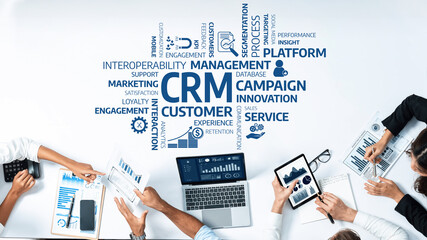 Poster - A top-down view of a business meeting discussing CRM strategies. Professionals analyze data and charts on laptops, emphasizing customer engagement and marketing effectiveness. Amity