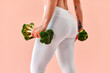 © HBS - Athletic girl doing glute exercises with broccoli instead of dumbbells. Creative advertising. Beautiful glutes, fitness woman working out.