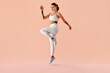 © HBS - Beautiful young athletic woman in white activewear jumping in the air, isolated on light studio background. Dynamic fitness pose, energy, strength, confidence, modern healthy lifestyle concept.