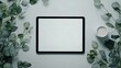 © Lilimanatasa - A mockup of a blank tablet screen sitting on a grey desk, with a cup of coffee and eucalyptus leaves beside it