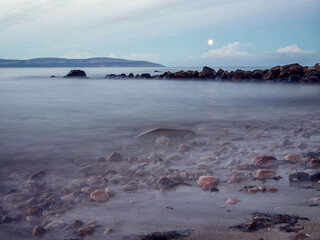 Wall Mural - View on peaceful Galway bay and Burren mountains from rough stone coast. Water surface is smooth and gives relaxing feel and mood. Irish nature landscape scene. Nobody. Cloudy sky.