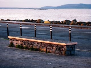 Wall Mural - solid stone bench by a car park with view on ocean and mountains in the background. travel and touri
