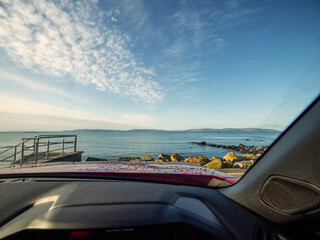 Wall Mural - View from a driver seat in a car on a Galway bay and Burren mountains and blue cloudy sky. Silverstrand area of Galway city. Travel and tourism. Rent car for trip concept. Landmark in Ireland.