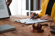 ©  NCST Studio - Lawyer showing contract details to client using pen, with gavel and legal documents on wooden desk