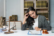 ©  NCST Studio - Young asian lawyer holding her head with hand looking stressed while working on a difficult case in her office