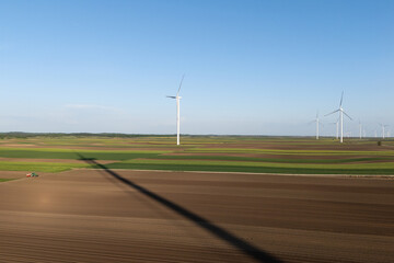 Aufkleber - Agricultural tractor is working on the field with wind turbines. Aerial view