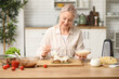 © Pixel-Shot - Beautiful mature happy woman cooking delicious lasagna at table in kitchen