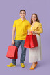 © Pixel-Shot - Beautiful young couple with red shopping bags on lilac background