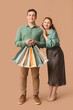 © Pixel-Shot - Beautiful young couple with shopping bags on brown background