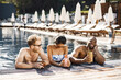 © prostooleh - Three friends in a swimwears relaxing near swimming pool