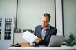 © laddawan - Confident businessman working on finance analysis with a tablet and laptop at office desk. Perfect for business