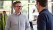 © Adi - Smiling men in business casual attire with glasses engaged in a friendly conversation in a modern office