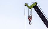 boom of a crane with a hook and cables against the sky
