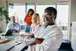 © Flamingo Images - Happy business team collaborating in a modern bright office environment. A smiling black man sits confidently adding warmth and energy to the group.