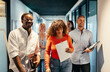 © Flamingo Images - Diverse group of smiling professionals walking through modern office hallway. Energetic mood, casual business attire, teamwork vibe