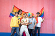 © Pituk - Happy group of young Asian friends having fun while holding rainbow flags celebrating Gay Pride Day, standing on pink background - LGBTQ community concept