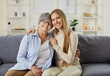 © Studio Romantic - Family portrait of senior woman and her adult daughter posing on comfortable sofa at home, embracing and smile gently, have good relationships. Two generations. Family bonding concept