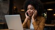 © Oxana39 - Young woman working on laptop and talking on smartphone in cozy cafe. Focused expression, casual outfit, warm lighting, and modern interior in background.