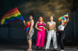 © Pituk - Young diverse lgbtq friends wearing colorful clothes, posing with gay pride rainbow flag at studio, pride month. People lifestyle fashion lgbtq concept