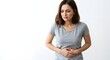 © Thiago - A woman in a gray shirt holds her stomach with a pained expression against a white background space
